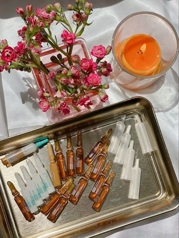 Flat lay of candle, flowers and ampoules on silver tray
