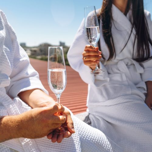 flirting couple with sparkling wine on a roof, close angle